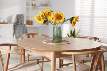 Beautiful sunflowers in vase on dining table at home