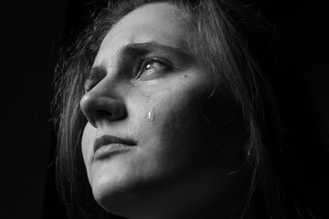 Fototapeta premium Sad woman crying on dark background, closeup. Black and white effect