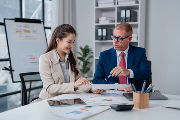 Business colleagues collaborating at an office desk, analyzing documents and charts, fostering teamwork and professional communication between diverse team members
