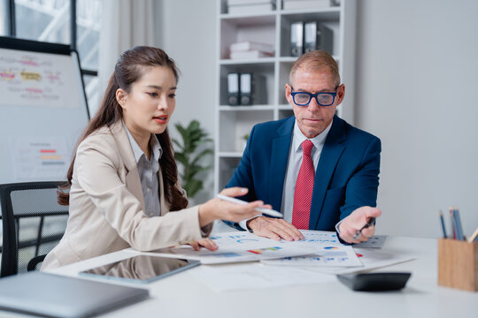 Business colleagues are collaborating on data analysis, discussing charts and graphs on printed reports during a corporate meeting in a modern office environment