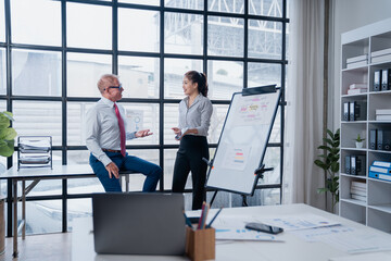 Business colleagues collaborating and discussing ideas near a whiteboard with charts, sharing insights and working together on project planning in a modern office environment
