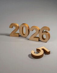 Slightly stylish wooden numbers '2026' placed on a smooth gray background, with an additional number '5' lying separately.