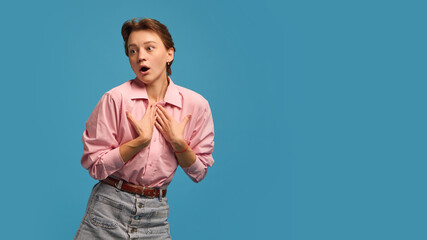 Young woman expressing surprise and confusion holding hands near chest. Concept of self-awareness,...