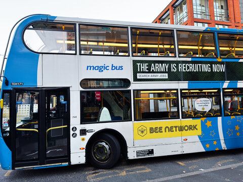 Manchester city double decker bus with army recruitment banner and yellow bee network ad