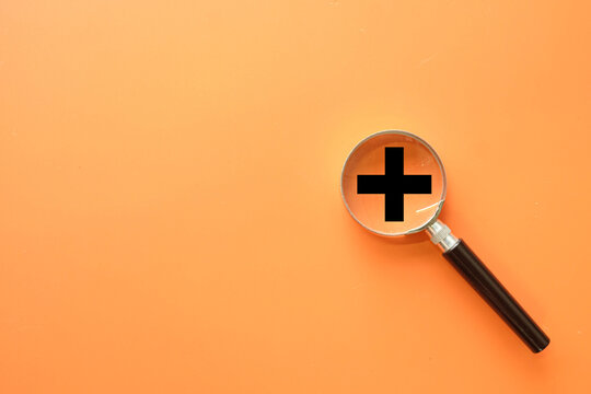 Adding value and creative business growth concept. A magnifying glass over a plus symbol, representing a focus on innovation, adding new features, and increasing company profit and success.