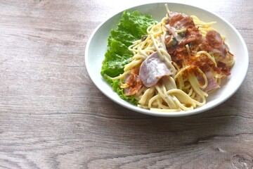 fried spaghetti white cabonara cream sauce topping slice crispy pork bacon and lettuce on plate 
