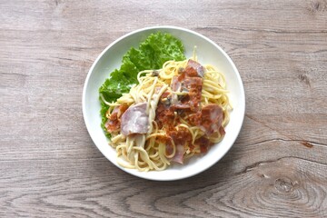 fried spaghetti white cabonara cream sauce topping slice crispy pork bacon and lettuce on plate 
