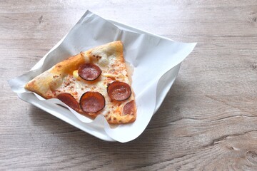 piece of baking homemade peperoni pizza topping slice salami on paper in plate 