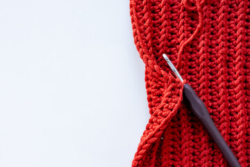 Red crochet project with hook on white background with copy space for text
