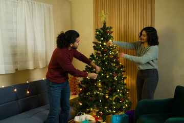 Couple decorating christmas tree together for holiday celebration