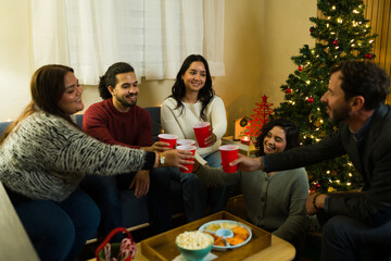 Happy colleagues celebrating christmas holidays making a toast with red cups