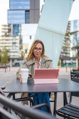 Woman working on tablet at outdoor cafe checking emails