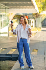 Woman taking selfie with smartphone drinking coffee urban
