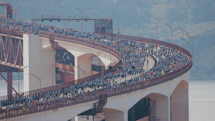 Running Lisbon half marathon crossing the 25 of April bridge over the Tagus river aerial view from above.
