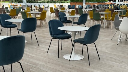 Empty cafeteria with modern furniture and colorful chairs in a spacious setting during daytime