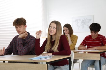 Students taking exam at wooden table indoors