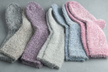 A cozy row of fluffy pastel socks lies on a light background, evoking warmth, comfort, and a sense of gentle winter relaxation.
