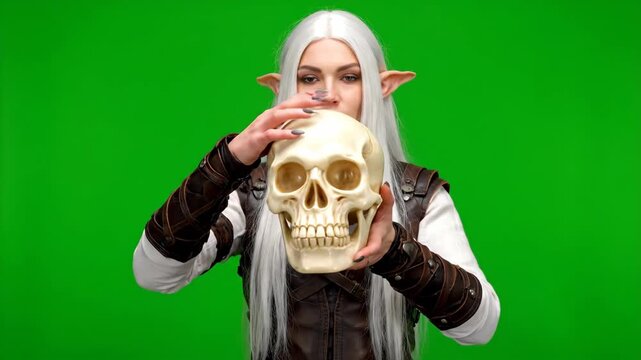 Elf Holding a Skull Ornament - An elf with white hair and pointed ears is holding a large skull-shaped ornament in front of her face.
