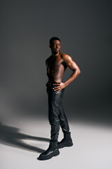 Naklejka premium Muscular man showcases strength and confidence in a studio setting