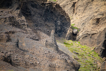 Rugged Volcanic Landscape with Eroded Rock Formations and Sparse Greenery