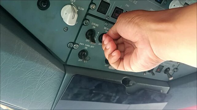 Video of a pilot&rsquo;s hand operating the beacon light control switch in a commercial aircraft cockpit, illustrating aviation technology and flight operations