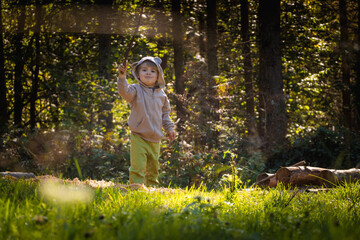 Little boy plays with sticks while walking in the forest