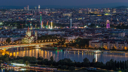 Aerial panoramic view over Vienna city with skyscrapers, historic buildings and a riverside promenade day to night timelapse in Austria.