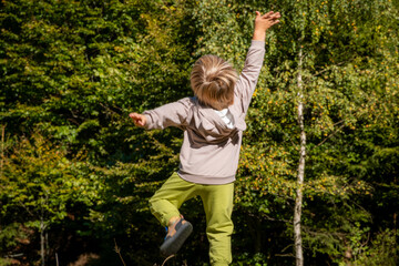 Delighted boy jumps for joy in the forest