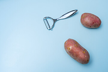 Hand peeling potatoes with a finger-safety peeler on a granite surface with a ceramic bowl
