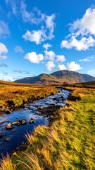 A tranquil stream winds through autumnal highlands, under a vibrant blue sky