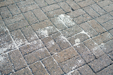 Deicing rock salt on concrete paving slabs, urban winter maintenance work to ensure pedestrian safety and prevent frost and ice accumulation