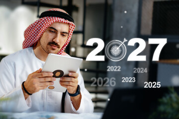 Focused businessman plans goals for the upcoming year while using a tablet