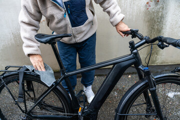 Naklejka premium Nach der Wäsche Detailaufnahme einer Person, die den nassen schwarzen Fahrradrahmen mit einem Tuch abtrocknet