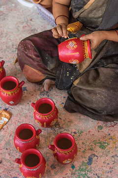 Potter painting a clay pot, Traditional Indian earthenware Handmade pottery, Freshly fired and hand painted Clay products for Diwali festival, Pune, Maharashtra, India.