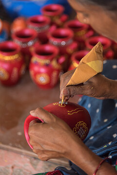 Potter painting a clay pot, Traditional Indian earthenware Handmade pottery, Freshly fired and hand painted Clay products for Diwali festival, Pune, Maharashtra, India.