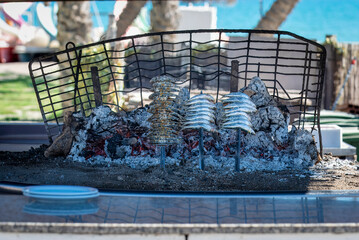 Charcoal grilled fish on skewers being cooked