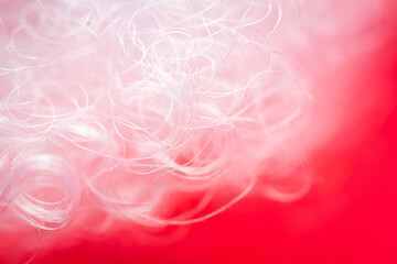 Extreme macro of polyester stable fiber on red background. Selective focus, shallow depth of field. Abstract dreamy background