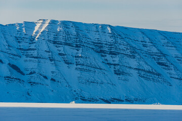 Majestic Greenland mountains covered in snow under a clear sky showcasing nature's beauty and tranquility