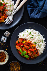 Polish lecho with white rice - bell pepper tomato stew with sausages on black table. Top view