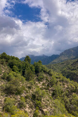 Fototapeta premium Scenic view of surrounding mountains and picturesque village from a hiking trail along an old irrigation ditch in Frigiliana, Spain.