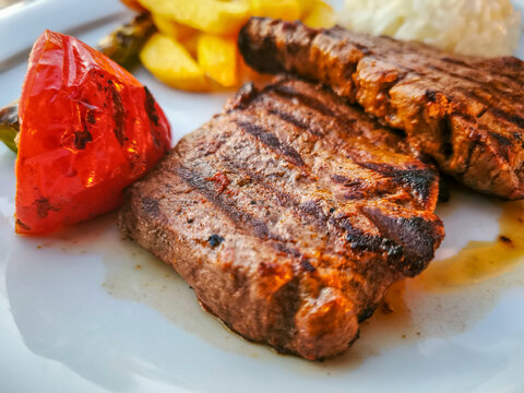 Turkish style meal. Rice, fried potatoes, tomatoes and lamb chops on a white plate.