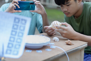 Asian student is cutting ArUco markers to prepare a turntable for 3D photogrammetry scanning of...