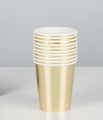 Stacked gold plastic glasses isolated nature background with clipping path