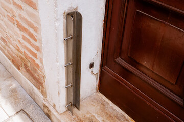 Metal door frame reinforcement plate installed on damaged wooden doorway with exposed brick wall showing home security improvement and burglary prevention hardware