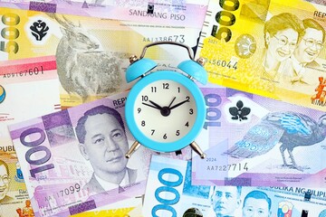 Philippines peso currency money bills and alarm clock. The concept of time management and income