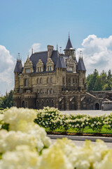 Obraz premium Majestic historic mansion surrounded by blooming flowers on a sunny day with blue skies