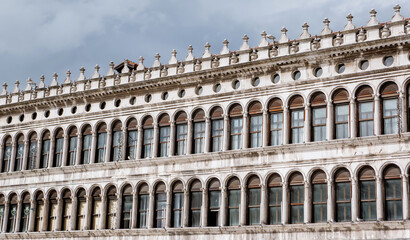 Historic Renaissance Facade with Symmetrical Arched Windows in Venice, Italy – Classical Architecture and Ornate Stone Detailing Under Cloudy Sky