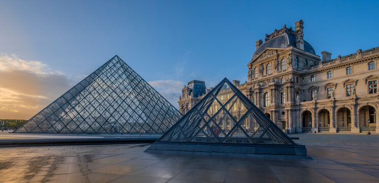 Paris, France - October 04 2025: The famous Louvre Museum in Paris showcases its iconic glass pyramids against a stunning sunset sky