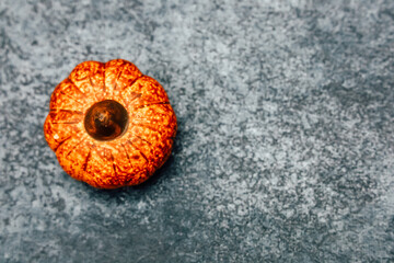 Bright orange pumpkin on a textured gray surface in a seasonal autumn setting