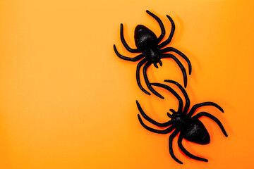 Black plastic spiders on bright orange background for Halloween decoration ideas